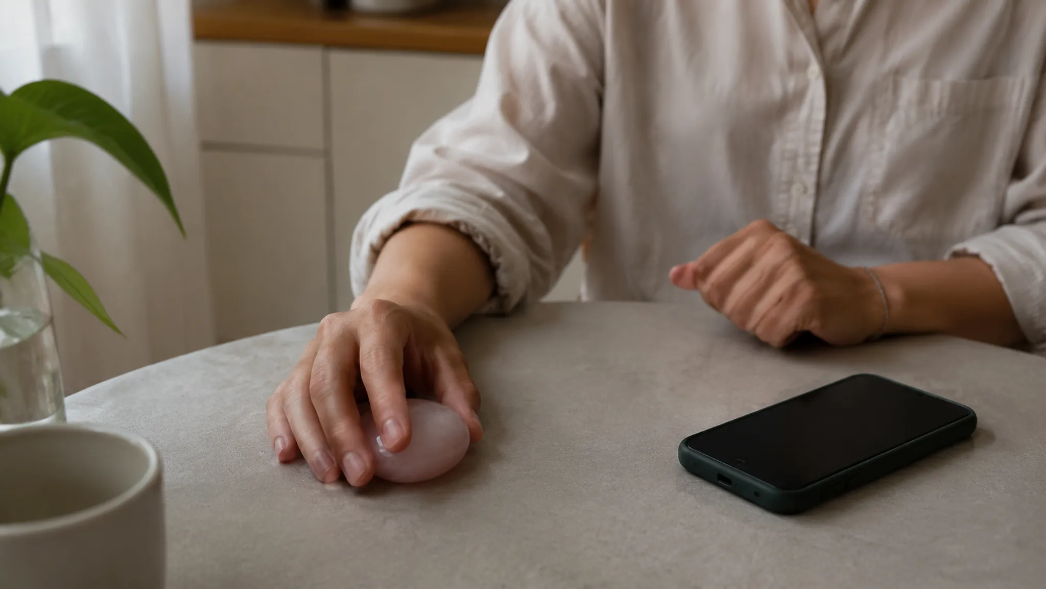 A phone placed face down beside a small tactile object used as a pause before the next screen action